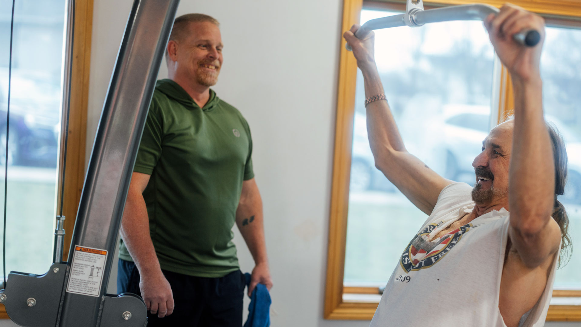 Barbour Health trainer spotting patient on weight machine.