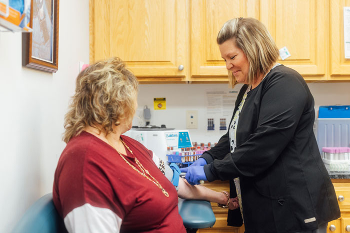 Female doctor taking patients blood pressure.