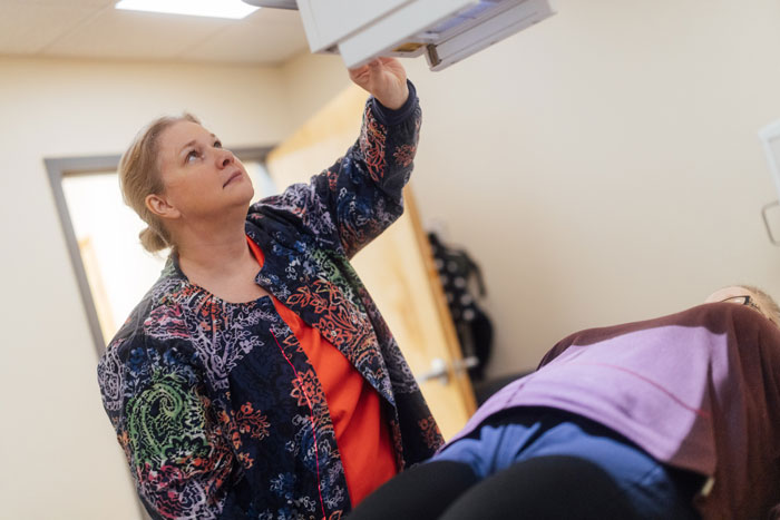 Radiologist using X-ray machine on patient.